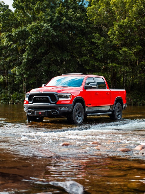 A red Ram 1500 drives through the water.